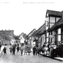Bismarckstraße widok w stronę Bahnhofstraße - ul. 28-go Lutego, po prawo zajazd - gospoda Carl'a Bunde. W tle widoczny duży budynek browaru Riemera. Fotografia z 1915 roku